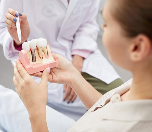 Patient holding a dental implant model while dentist points
