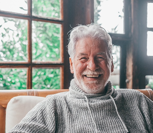 Man smiling while sitting in a wood chair