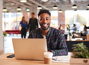 Man smiling while working on laptop in office