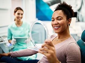 Woman smiling at reflection in handheld mirror
