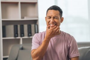 Young man holding his mouth in pain.