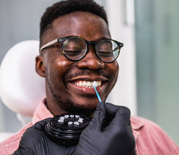Dentist holding a veneer to a smiling mans teeth