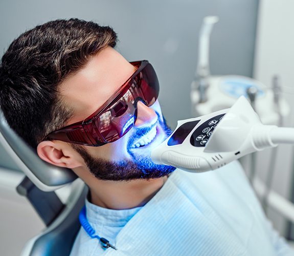 Man in dental chair getting his teeth professionally whitened